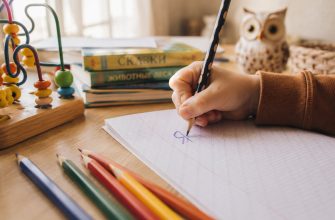 Ребенок пишет буквы зеркально — крупный план руки, выводящей букву Я в обратную сторону в школьной тетради.
